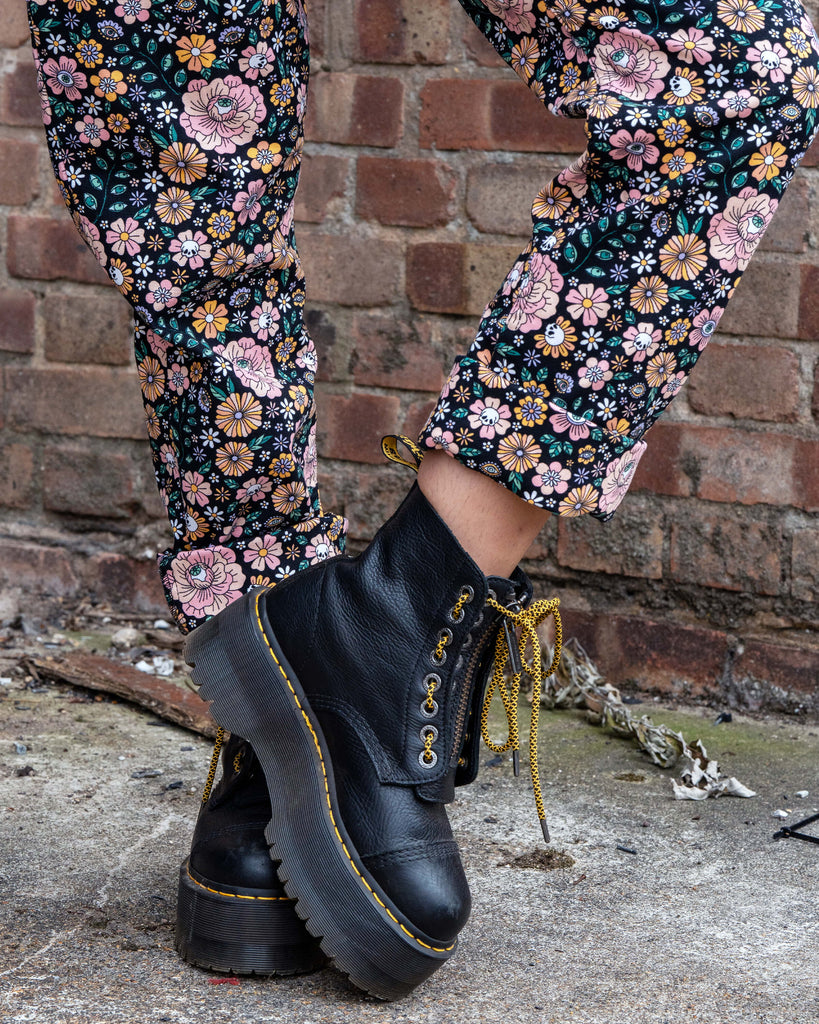 Close-up of the Eye Spy Floral Dungarees fabric showing detailed pink and mustard flowers with mystical eyes and skull motifs on black stretch twill.