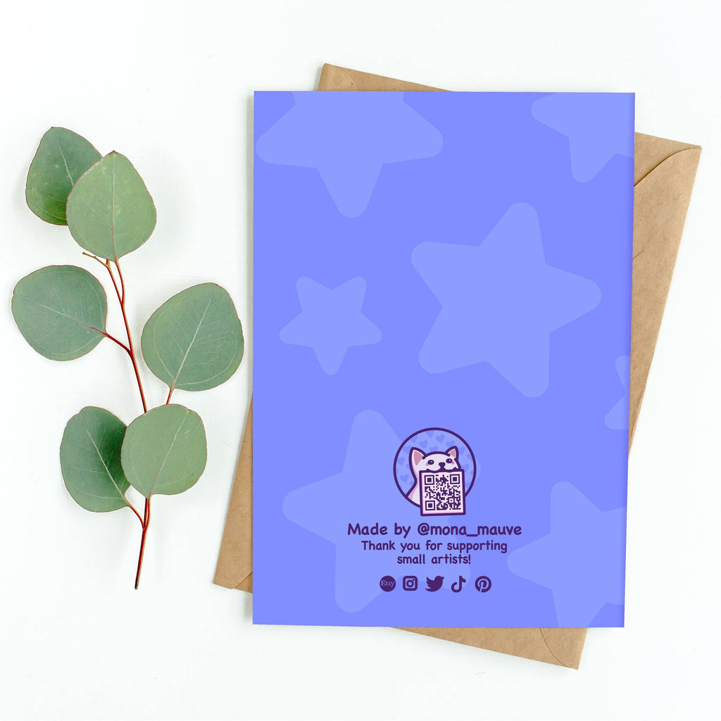 Back of a purple birthday card with a star pattern, designed by Mona Mauve for Rebel Romance. Features a cute cat logo with a QR code and the text “Made by @mona_mauve – Thank you for supporting small artists!” Icons for Etsy, Instagram, Twitter, TikTok, and Pinterest are shown at the bottom. The card is displayed with a kraft brown envelope and eucalyptus leaves on a white background.