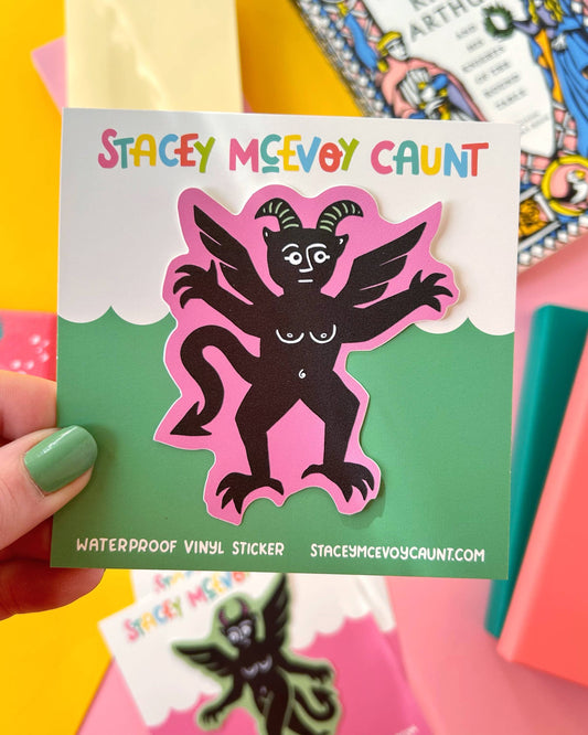 A Pink Devil Sticker by Stacey McEvoy Caunt shown on its branded backing card with the colourful Stacey McEvoy Caunt logo above and product info below. The sticker features a whimsical six-armed devil with wings and horns, in black on a pink background. Books and bright stationery surround the product. Sold by Rebel Romance, an alternative UK brand.