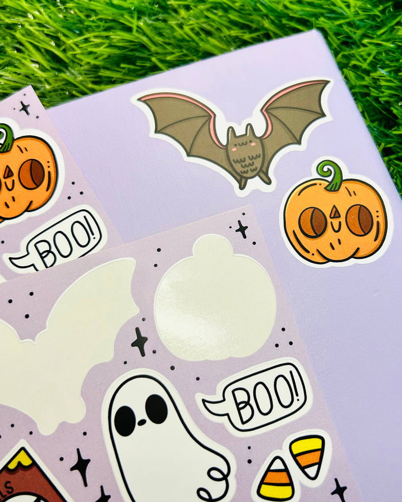 Close-up of Rebel Romance Spooky Cuties Matte Vinyl Sticker Sheet by Kelly Lou, featuring Halloween-themed stickers including a bat, pumpkin, ghost saying “BOO!”, and candy corn. Printed on pastel purple with a soft matte finish, perfect for decorating notebooks, laptops, and spooky scrapbooks. Ideal for gothic stationery lovers and Halloween fans.