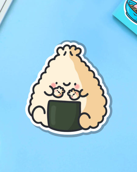 Cute vinyl sticker featuring a smiling dumpling turned onigiri character holding two tiny dumplings, designed by Toastedink. Set against a blue background, this sticker is perfect for laptops, bottles, and notebooks. Sold by Rebel Romance, a UK brand for quirky, alternative millennial style lovers.