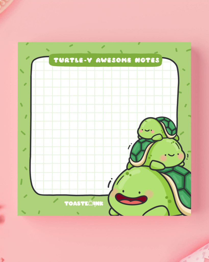 Adorable turtle sticky notes with a trio of cartoon turtles stacked on the bottom right corner. The design includes green grid lines and reads “Turtle-y Awesome Notes.” Sold by Rebel Romance UK, ideal for cute stationery lovers and fans of Toastedink's whimsical style.