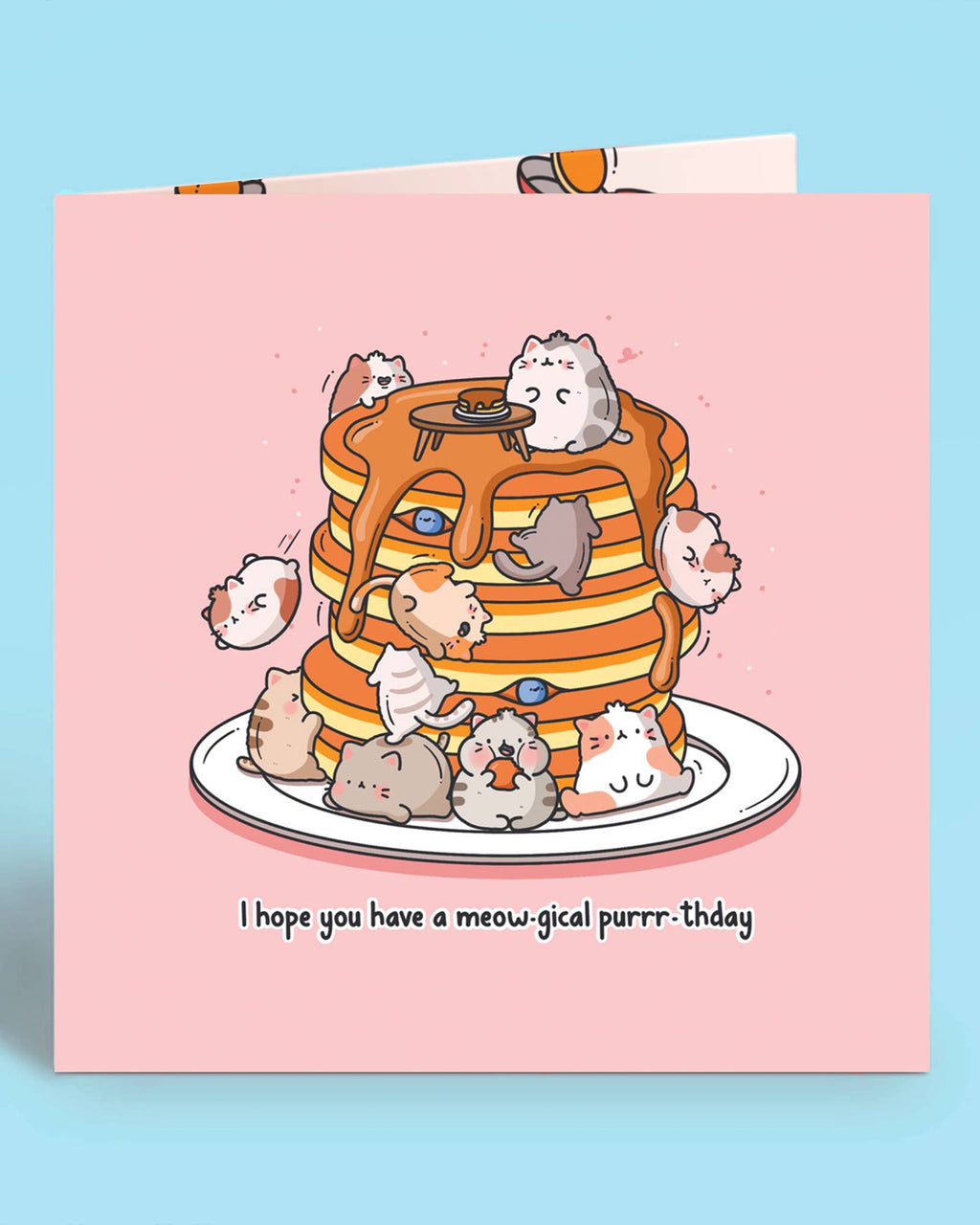Close-up of a square pink birthday card with cute illustrated cats on a pancake stack and the pun “I hope you have a meow-gical purrr-thday.” Ideal for cat lovers. Designed by Toastedink and stocked by Rebel Romance, a UK brand for quirky, nostalgic gifts.