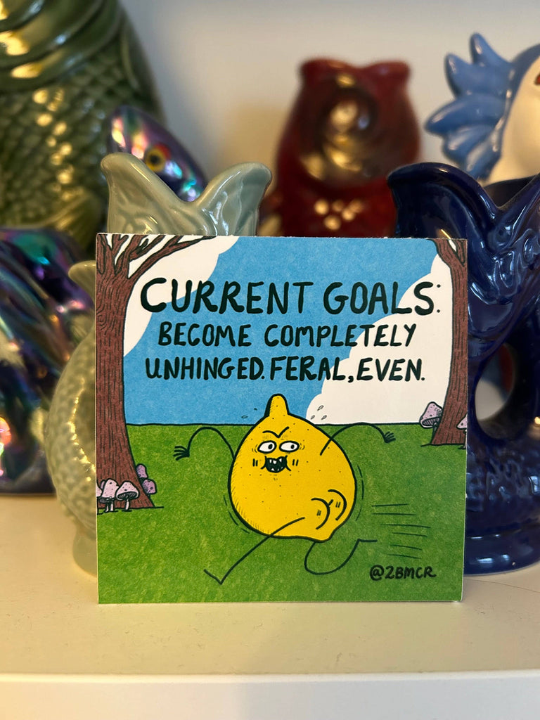 Cartoon card with a yellow cat and humorous text, surrounded by decorative items.