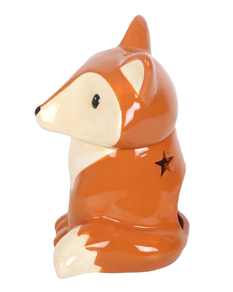 Side view of the ceramic fox-shaped oil burner and wax warmer from Rebel Romance. The fox features a glossy orange and cream finish with a star-shaped cut-out on its back and a charming woodland design.