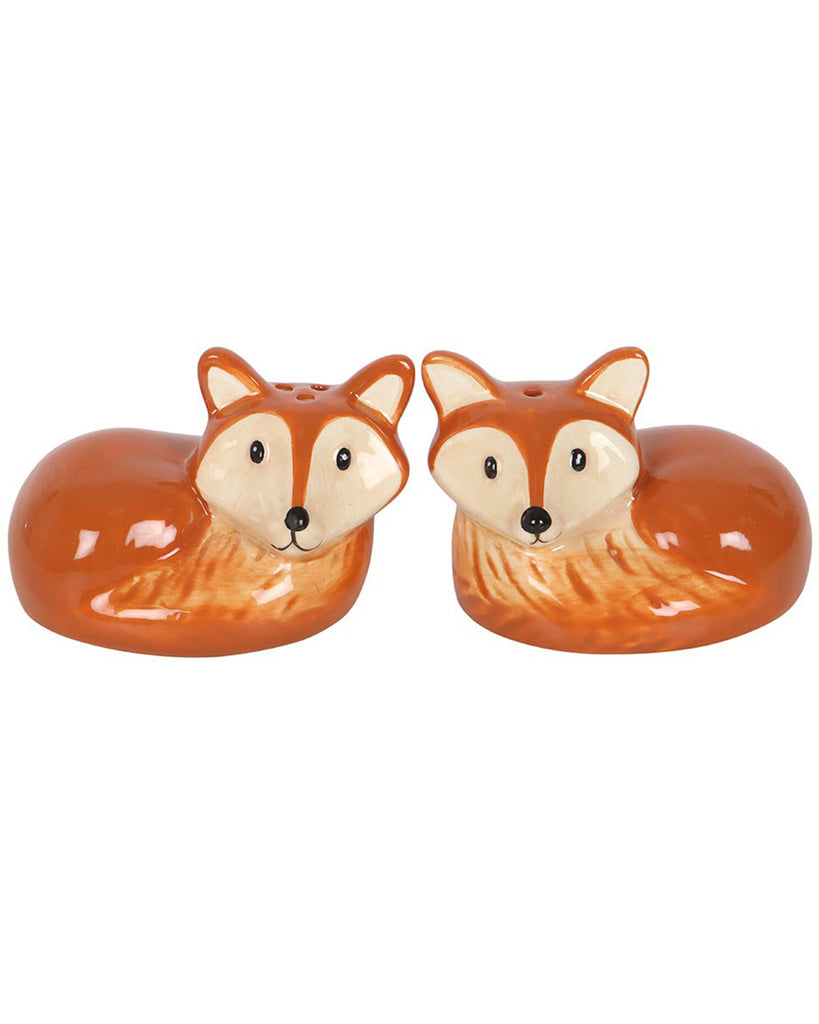 Close-up of two ceramic fox-shaped salt and pepper shakers with orange fur and cream accents, facing forward against a plain white background.