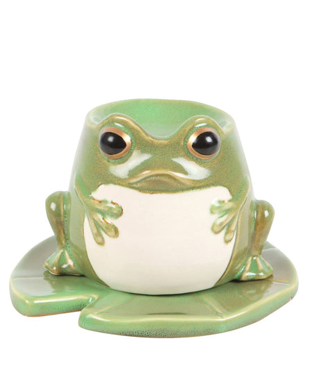 Front view of a green ceramic frog-shaped oil burner with black eyes and a white belly, sitting on a matching lily pad plate.