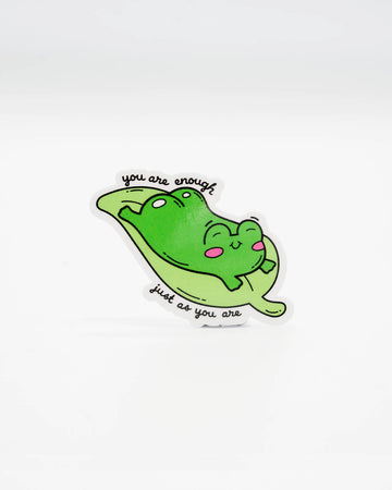 Cute die-cut vinyl sticker featuring a happy green frog lounging on a lily pad with the uplifting phrase “You are enough just as you are.” A sweet, motivational design perfect for laptops, journals, and self-love reminders. Created by Rebel Romance, a small UK brand that champions alternative style, quirky gifts, and feel-good millennial aesthetics.