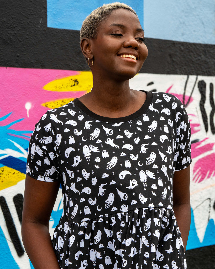 Close-up of Chish wearing the Rebel Romance Ghosties Smock Dress. The black stretch cotton fabric features white cartoon ghost prints with stars and moons, highlighting the round neckline and short sleeves.