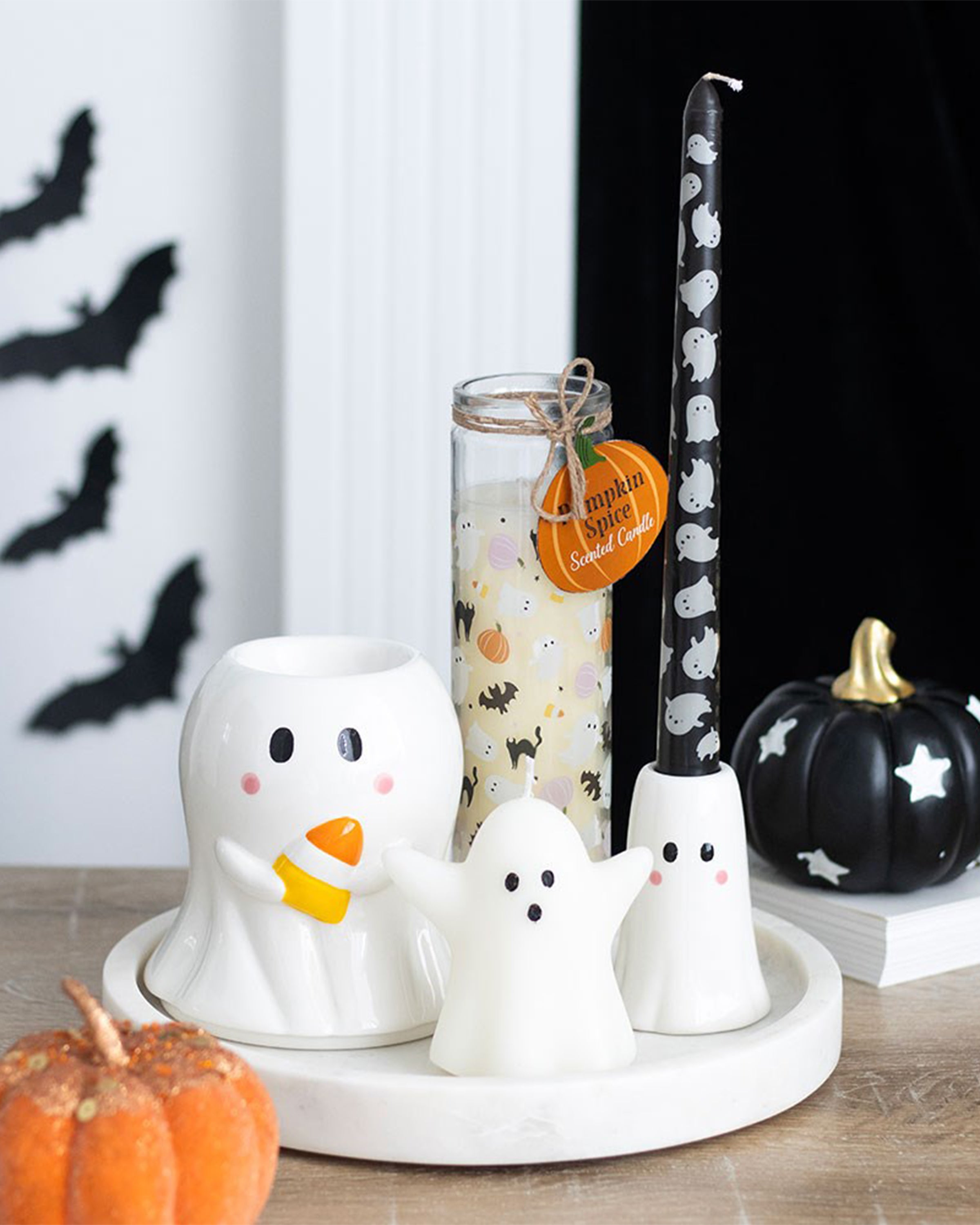 Ceramic ghost candle holder, black pumpkin, and sweet ghost-shaped candle on a white tray in a spooky Halloween setup, with bats on the wall. A perfect autumn aesthetic from Rebel Romance, a UK small business embracing alternative style.