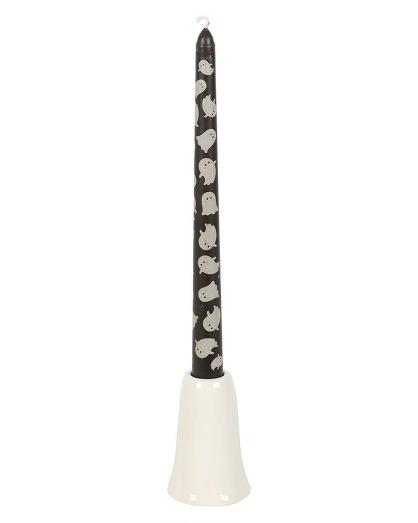 Front-facing image of the Rebel Romance Sweet Ghost Candle Holder with its black taper candle, which is printed with an all-over white ghost pattern. The candle sits neatly in the ceramic ghost-shaped holder with painted eyes and rosy cheeks.