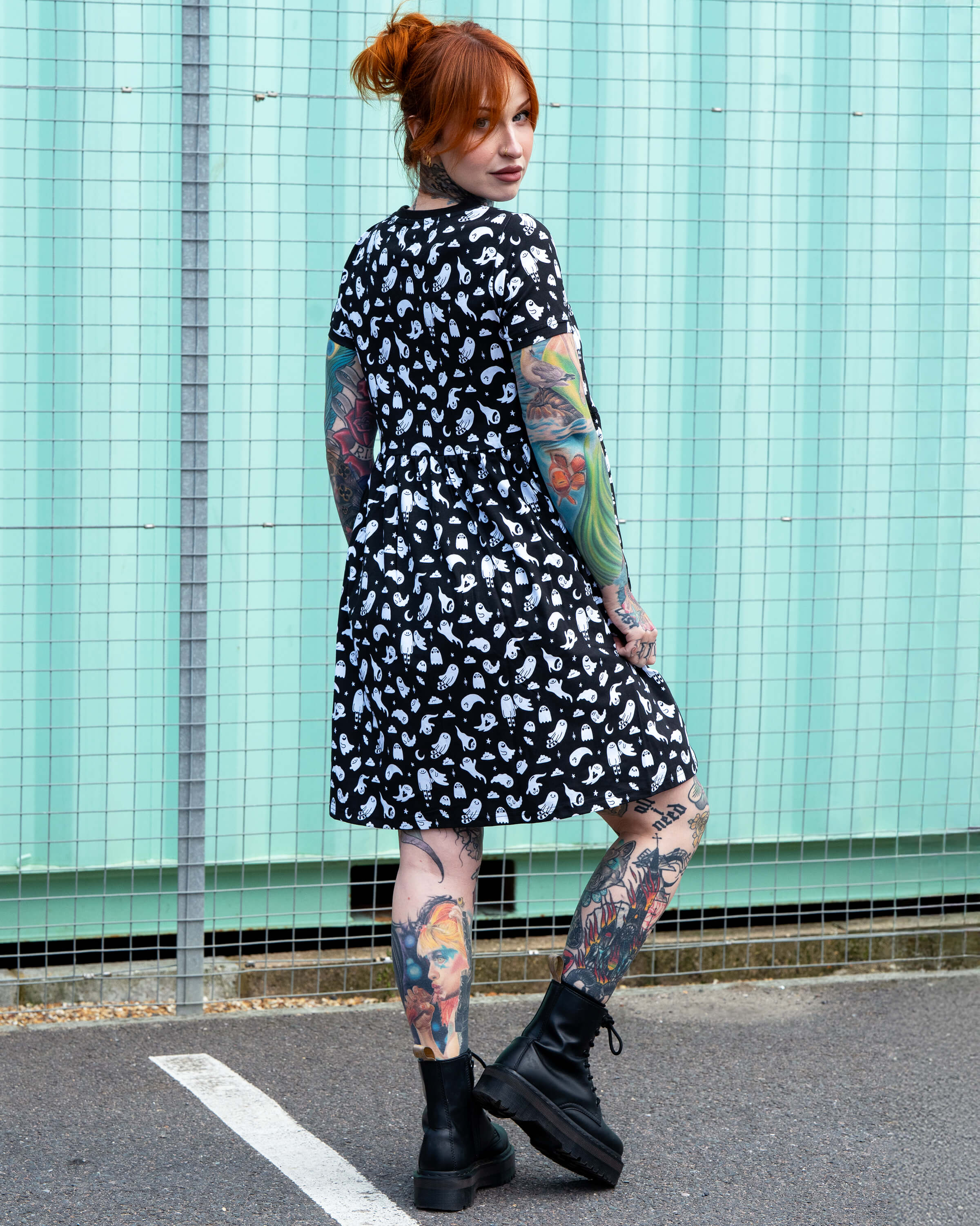 Back view of the Rebel Romance Ghosties Smock Dress worn by Erin. The black stretch cotton fabric is covered in a cute white ghost pattern, showing the relaxed fit and short sleeves.
