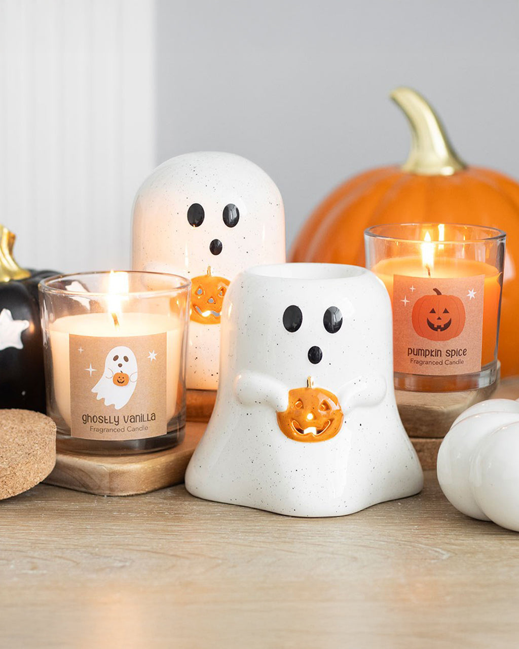 Ghostly Vanilla Candle by Rebel Romance, surrounded by Halloween-themed decor, including a ghost-shaped wax burner and pumpkin candles. The candle features a spooky ghost label with a pumpkin illustration.