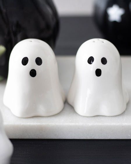 Lifestyle photo of the Rebel Romance ghost salt and pepper shakers on a marble tray, perfect for Halloween parties and gothic kitchen lovers.