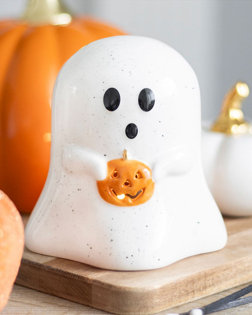 Rebel Romance ceramic ghost tealight holder styled on a wooden board with pumpkins in the background. Speckled ghost design with black eyes and a glowing orange pumpkin—perfect for cosy autumn or spooky season vibes.