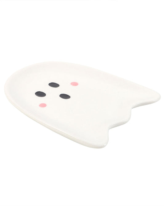 A ghost-shaped ceramic trinket dish by Rebel Romance, shown from an angled side view. The dish features a cute ghost face with black oval eyes and a mouth, plus pink blush cheeks, finished in glossy white ceramic. A quirky and spooky home décor piece, perfect for jewellery or small items.