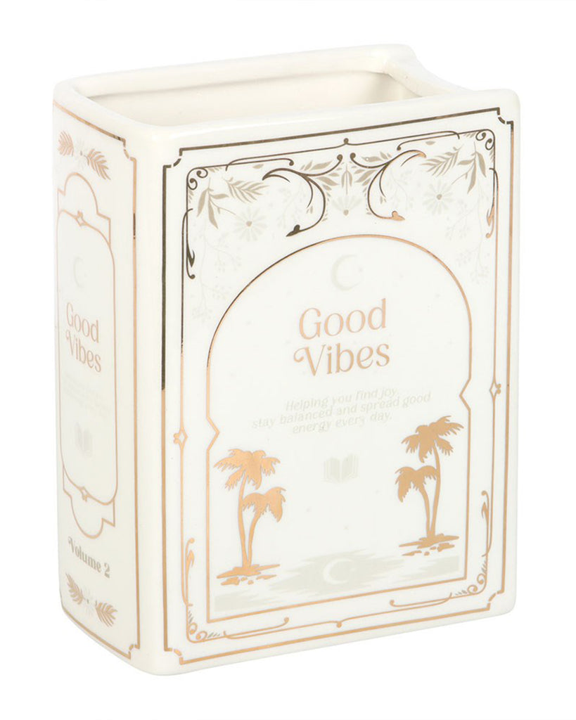 Side and front view of Rebel Romance Good Vibes White Book Shaped Vase with gold palm tree detail and the words “Good Vibes” on the cover design. A ceramic vase styled as an upright book, perfect for holding fresh or dried flowers in reading corners, shelves, or desks.