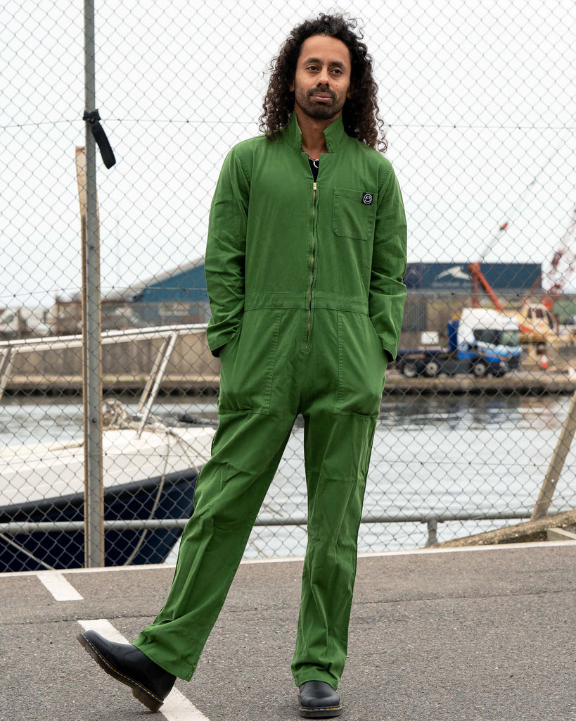Richard standing confidently in the Forest Green Boiler Suit by Rebel Romance with legs apart, showing the front zip and fitted waist detail.