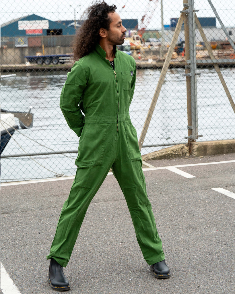 Richard standing confidently in the Forest Green Boiler Suit by Rebel Romance with legs apart, showing the front zip and fitted waist detail.
