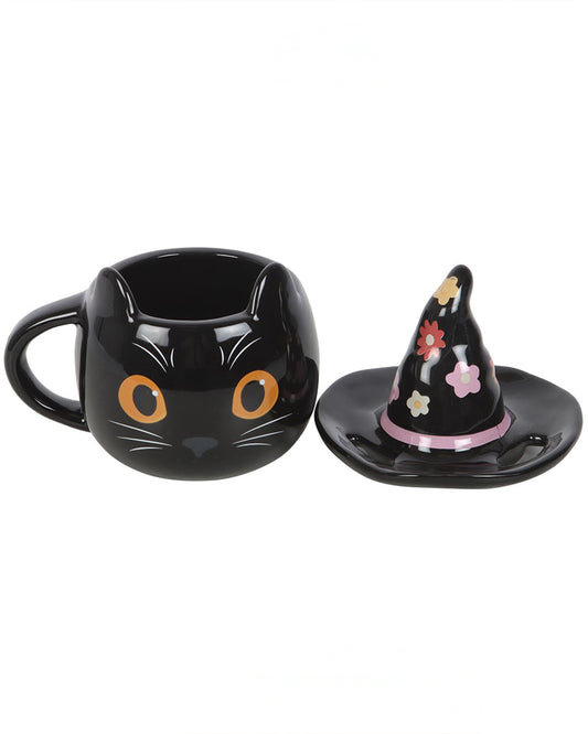 The Groovy Witch Cat Mug by Rebel Romance shown with the lid removed. The ceramic mug is shaped like a black cat with pointed ears and orange eyes, while the lid is a black witch hat with retro flower patterns. A fun and functional Halloween mug design.