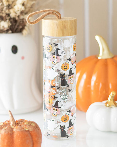 Rebel Romance’s Groovy Ghost Print Glass Water Bottle styled with pumpkins and autumn decor. The bamboo-lidded glass bottle features cute Halloween characters, blending retro aesthetics with modern sustainability. A spooky-chic autumn gift idea.