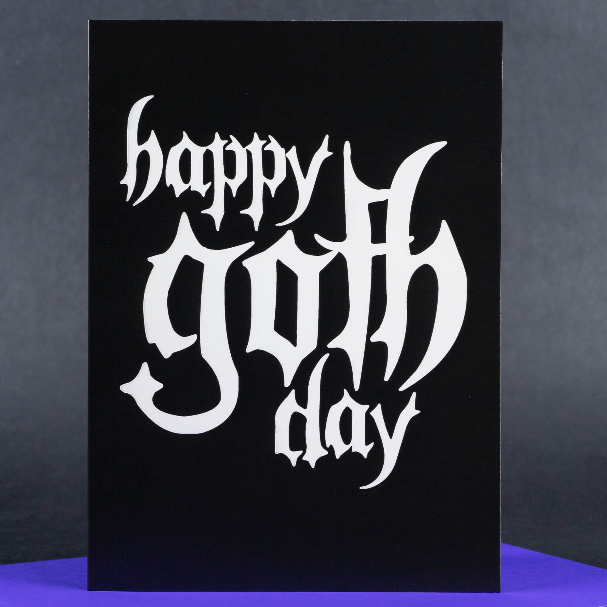 A striking minimalist greeting card with a black background and the words “Happy Goth Day” in dramatic, white gothic-style lettering. The bold contrast highlights the edgy aesthetic, perfect for celebrating in true goth fashion.