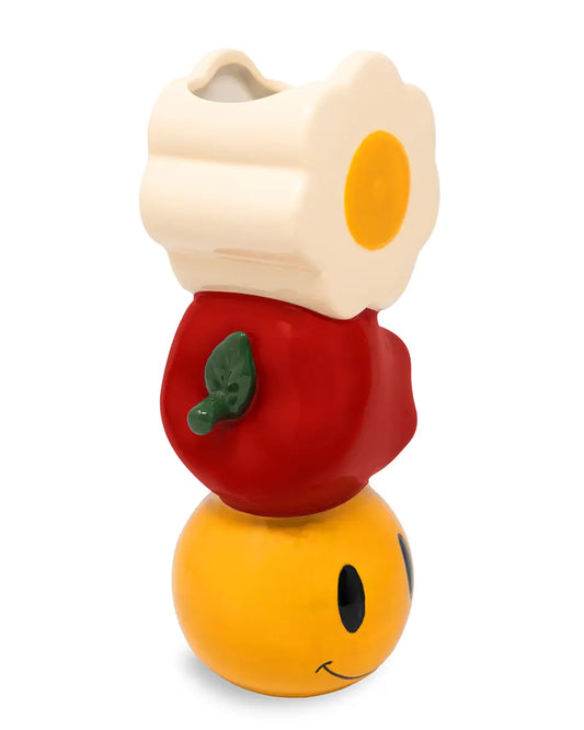 Ceramic Smiley Fun Vase from Rebel Romance featuring a stacked design with a yellow smiley face base, red apple centre, and daisy flower top. Quirky homeware ideal for kitchen tables, bookshelves, or desks. Perfect gift for fans of playful, retro-inspired aesthetics and alternative home décor.