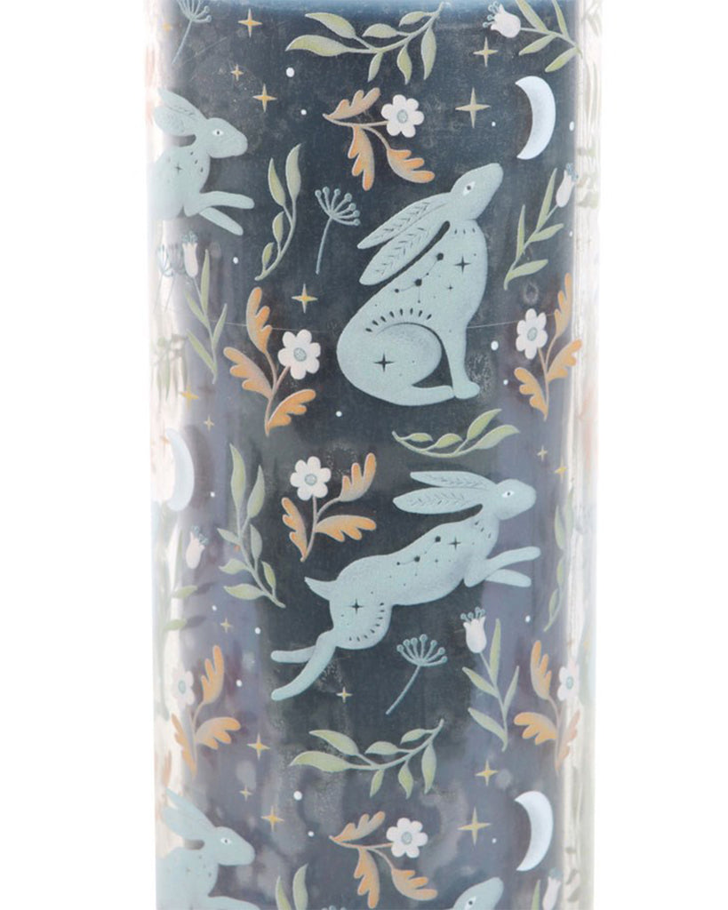 Close-up of the Midnight Hare Wild Tulip Tube Candle by Rebel Romance. The dark navy background highlights pastel blue moon-gazing and leaping hares, surrounded by wildflowers, crescent moons, and tiny stars.