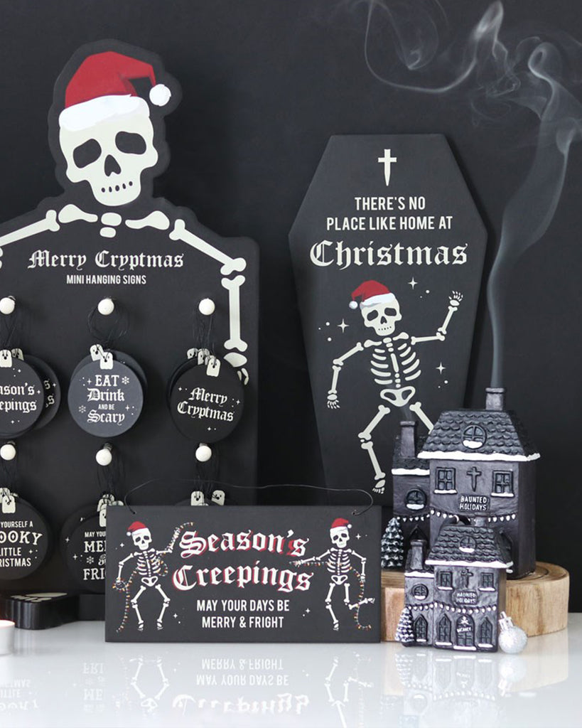 Black gothic-style Christmas display featuring skeleton-themed décor and signage from Rebel Romance, with a haunted holiday house incense burner releasing smoke.