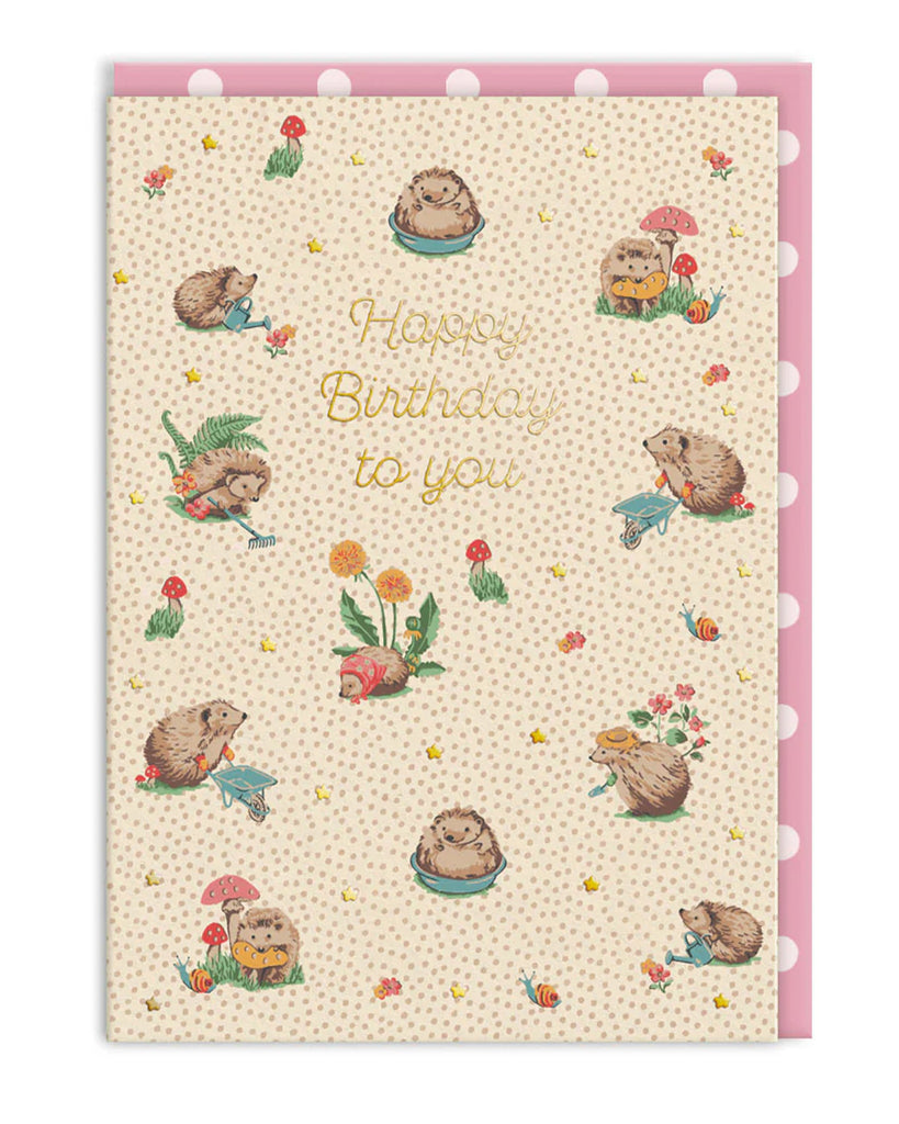 A cute A6 Cath Kidston birthday card from Rebel Romance featuring illustrated hedgehogs gardening, eating cake, and playing in a whimsical woodland scene. Gold foil "Happy Birthday to you" text in the centre, with a pink polka dot envelope included. Perfect for hedgehog lovers and fans of nostalgic, cottagecore aesthetics.
