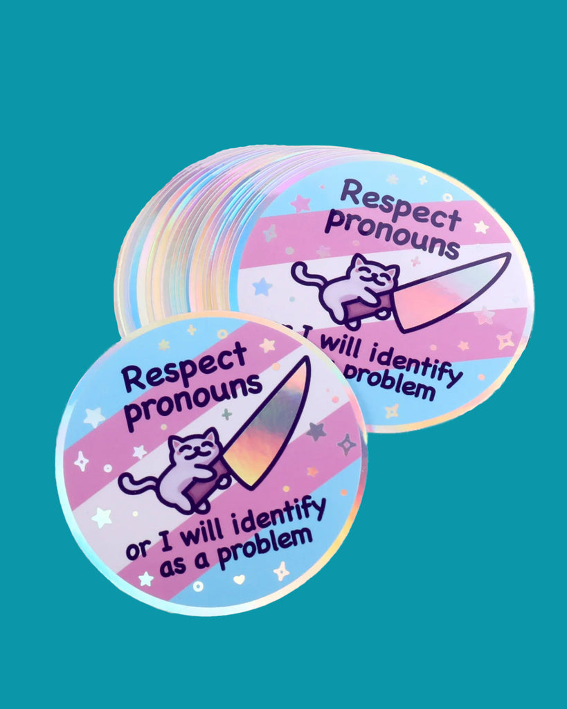 Round holographic vinyl sticker with a pastel trans pride flag background, featuring a cute cartoon cat holding a shiny knife. Surrounded by stars and sparkles, with the text “Respect pronouns or I will identify as a problem.” A bold and playful queer design by Mona Mauve, perfect for laptops, water bottles, or journals. Sold by Rebel Romance, a small UK business celebrating LGBTQIA+ pride and inclusive alternative aesthetics.
