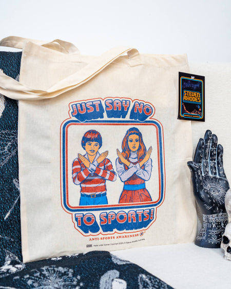 A natural cotton tote bag featuring a retro-style Steven Rhodes design with two children crossing their arms in an “X” shape and the text “Just Say No To Sports!” in bold, vintage-style lettering. The bag has a minimalist design with sturdy handles, perfect for daily use.