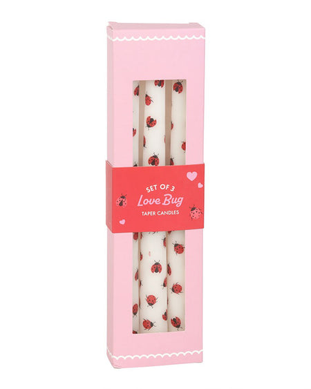 Front view of the boxed Love Bug Ladybird Taper Candles by Rebel Romance. The pink box features scalloped white detailing, heart illustrations, and a clear window showcasing the candles inside.