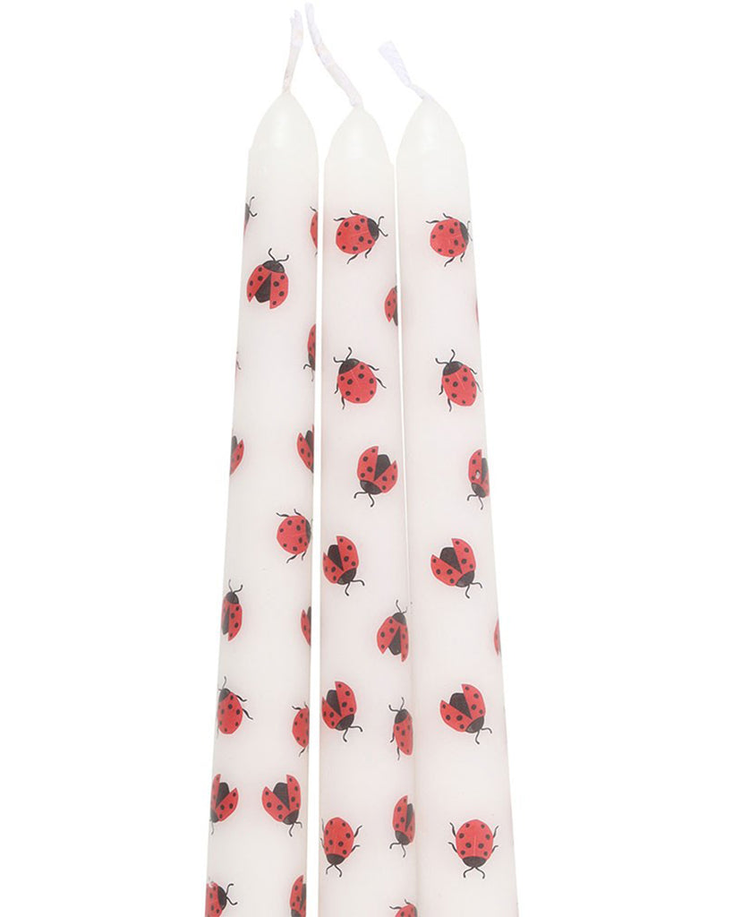 Full view of the 3 Love Bug Ladybird Taper Candles standing upright. Each candle features a repeated pattern of red ladybirds with black spots, some with wings closed and others slightly open.
