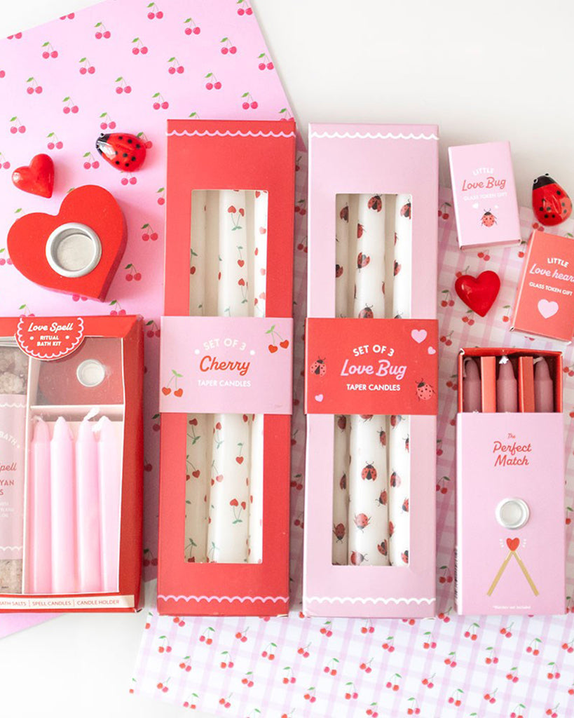 Flat lay of the Love Bug Ladybird Taper Candles alongside other Rebel Romance Valentine's Day gifts, including cherry-print candles, heart-shaped accessories, and matchstick sets.