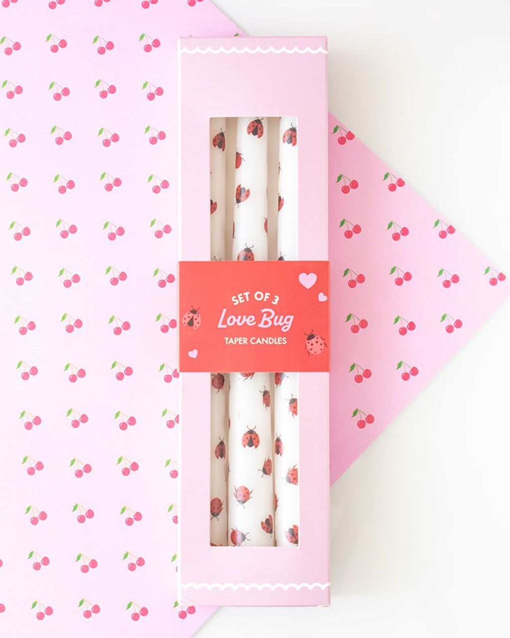 Set of 3 Love Bug Ladybird Taper Candles in pink packaging with a red label. The box has a clear window showing the white candles decorated with cute red and black ladybirds. Perfect for Valentine’s Day gifting or whimsical home decor.