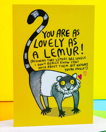 Bright yellow A6 greeting card by Rebel Romance featuring a hand-illustrated lemur with the message "You are as lovely as a lemur!" in playful black text. Designed by Katie Abey, the card includes quirky hand lettering and a whimsical lemur drawing with a striped tail, set against a cheerful background. Perfect for animal lovers and alternative stationery fans. Blank inside and printed in the UK.