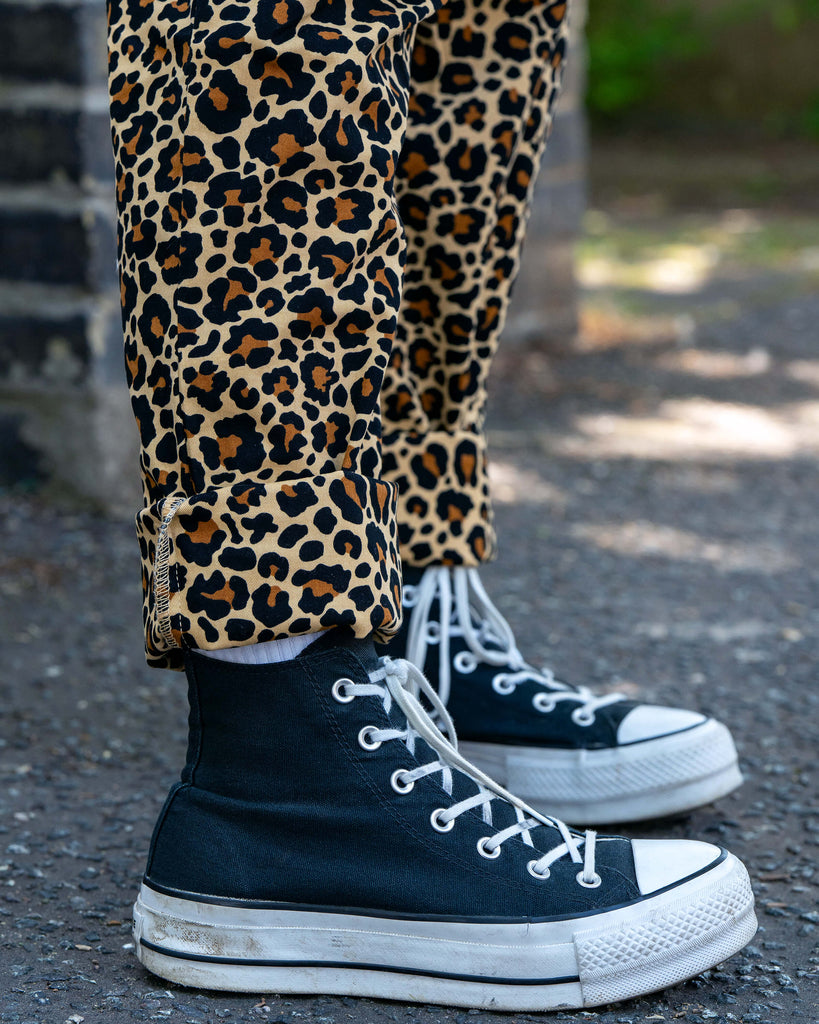 Close-up of the leopard print dungaree leg cuff and black high-top trainers. Rebel Romance Classic Leopard Print Stretch Dungarees showcase bold, alternative fashion for everyday wear.