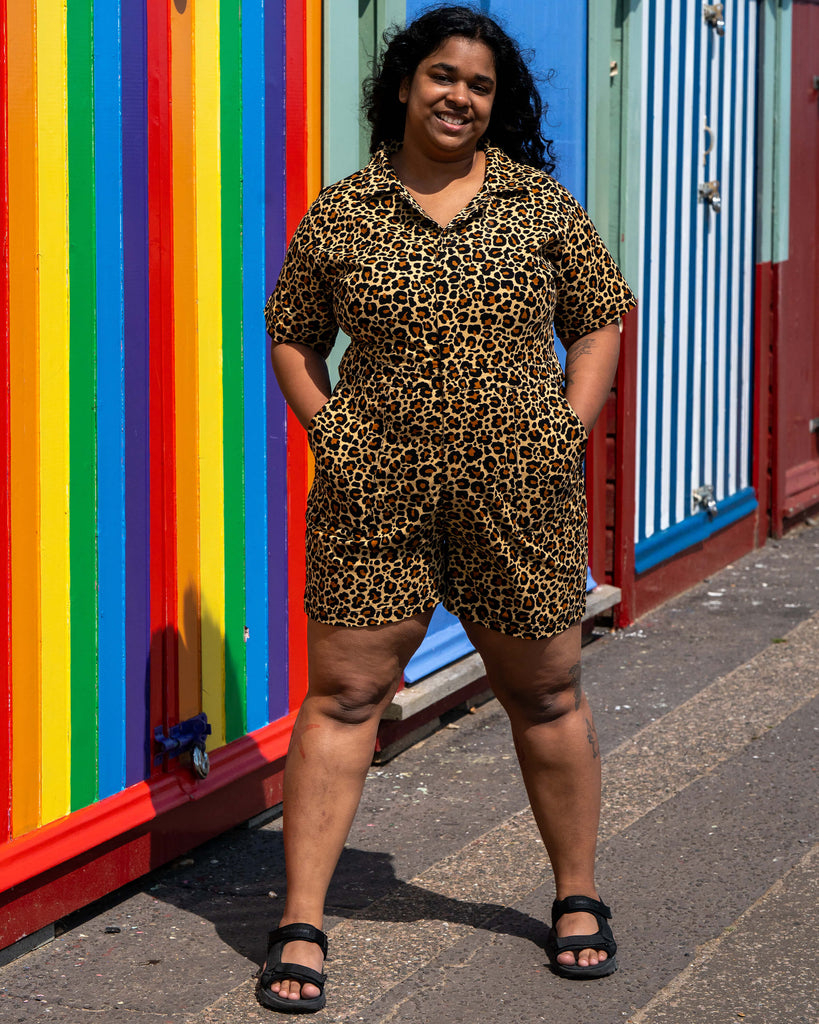 Vidhya smiles in front of rainbow beach huts in the Rebel Romance Classic Leopard Playsuit. This leopard print zip-up romper is the ultimate mix of boldness and comfort for summer dressing.