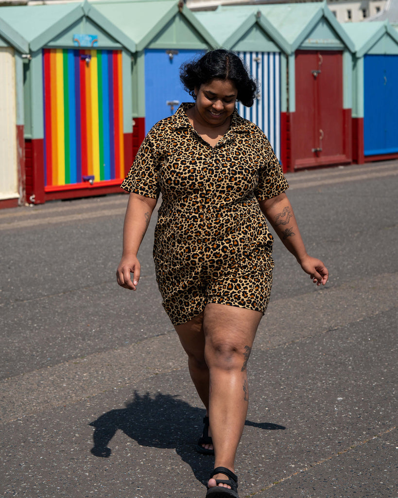Model Vidhya walks confidently past colourful beach huts in Brighton wearing the Rebel Romance Classic Leopard Playsuit. The short romper features a collared neckline and an all-over leopard print.