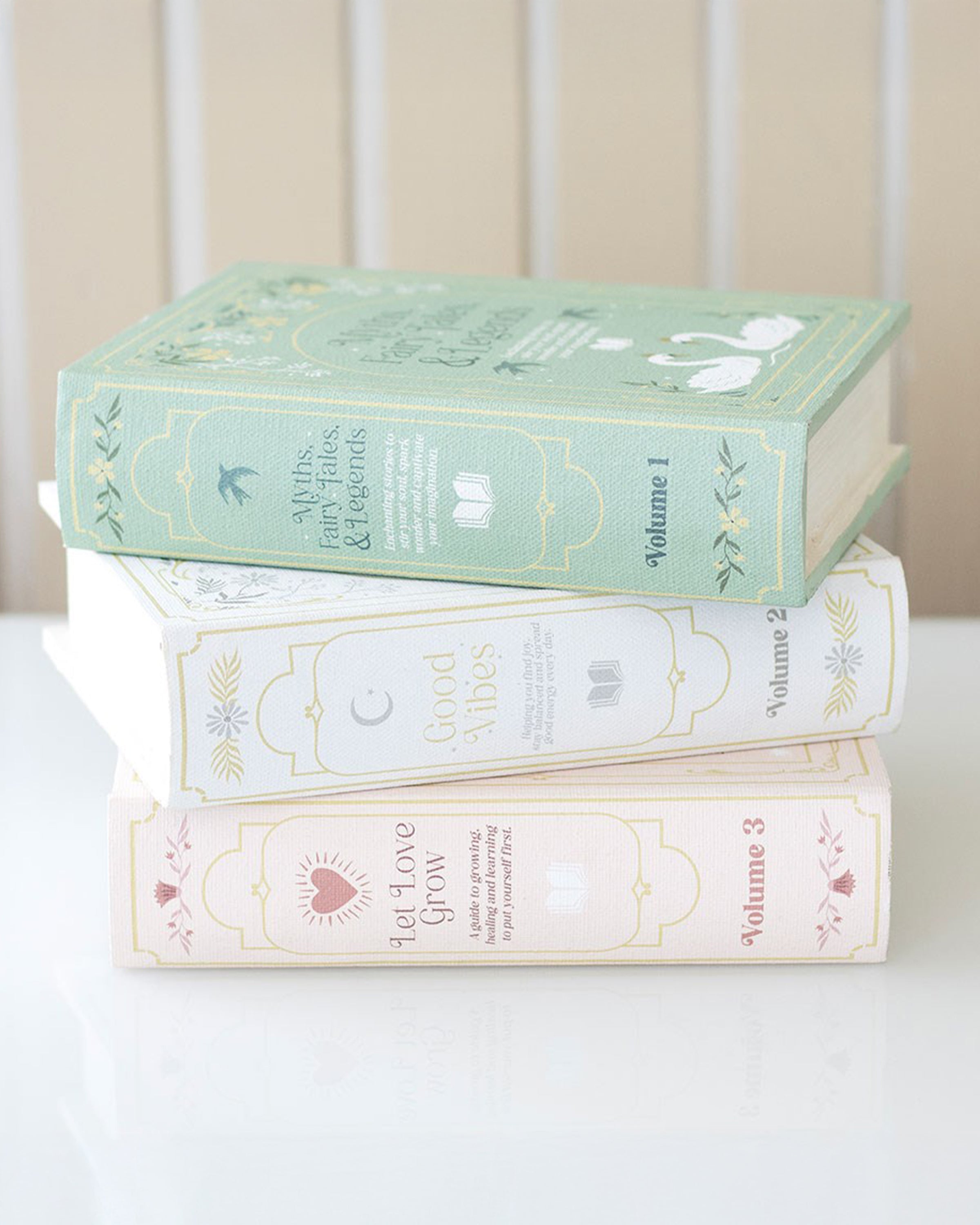 Set of three Rebel Romance book-shaped storage boxes stacked together: Myths, Fairytales & Legends in green, Good Vibes in white, and Let Love Grow in pink. These vintage-style storage boxes are perfect for home décor, book lovers, and hiding treasures in plain sight.