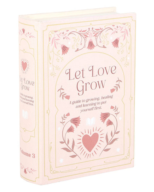 Side view of the Rebel Romance Let Love Grow book-shaped storage box in soft pastel pink with floral illustrations and embossed lettering. This hidden storage box looks like an elegant vintage book, perfect for book lovers, home décor, or gifting.