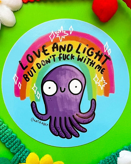 A round vinyl sticker by Katie Abey featuring a cute purple octopus under a rainbow with the text “Love and Light But Don’t F*ck With Me.” Sold by Rebel Romance, this sticker is ideal for laptops, bottles, or journals and adds a mix of spiritual sass and strong boundaries to your everyday essentials.