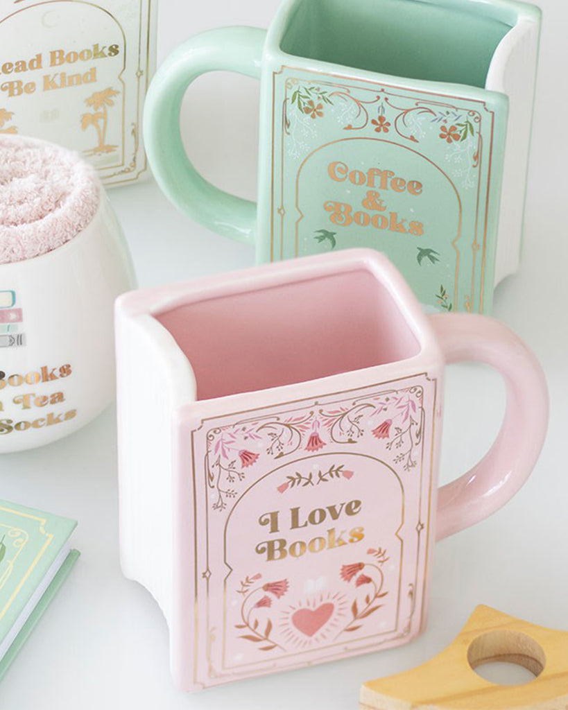 A pastel pink ceramic book-shaped mug from Rebel Romance with “I Love Books” in gold lettering, floral detailing, and a heart design. Perfect homeware gift for book lovers, millennials, and cosy tea or coffee moments.
