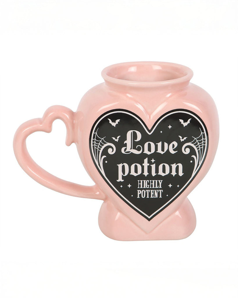 Angled view of the Rebel Romance Love Potion Shaped Mug, pink with a heart‑shaped handle and black gothic label reading “Love Potion Highly Potent.” A spooky‑cute ceramic mug for tea or coffee.
