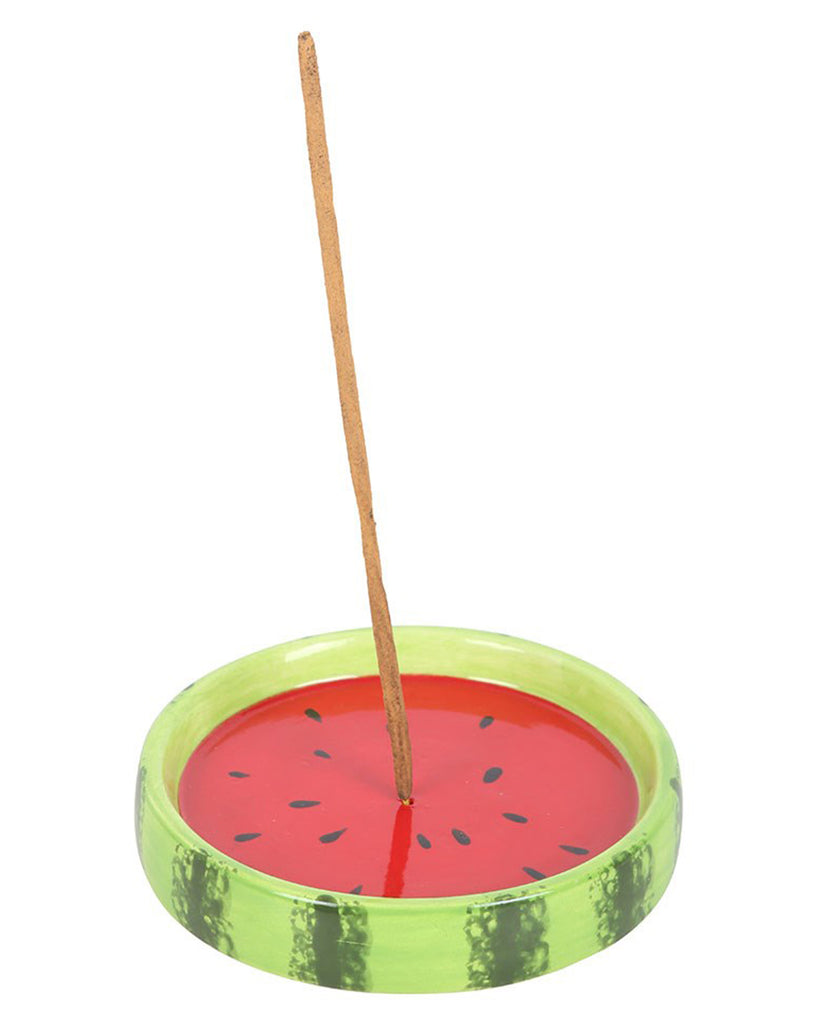 The ceramic watermelon incense holder with an incense stick inserted in the centre, showing how it holds and catches falling ash while burning.