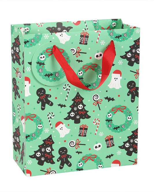 Alternative angle of the Merry Creepmas gift bag by Rebel Romance featuring festive spooky illustrations such as haunted wreaths, bats, gingerbread skeletons, skulls, ghosts, and gothic Christmas trees. Red ribbon handles and tag detail are visible.