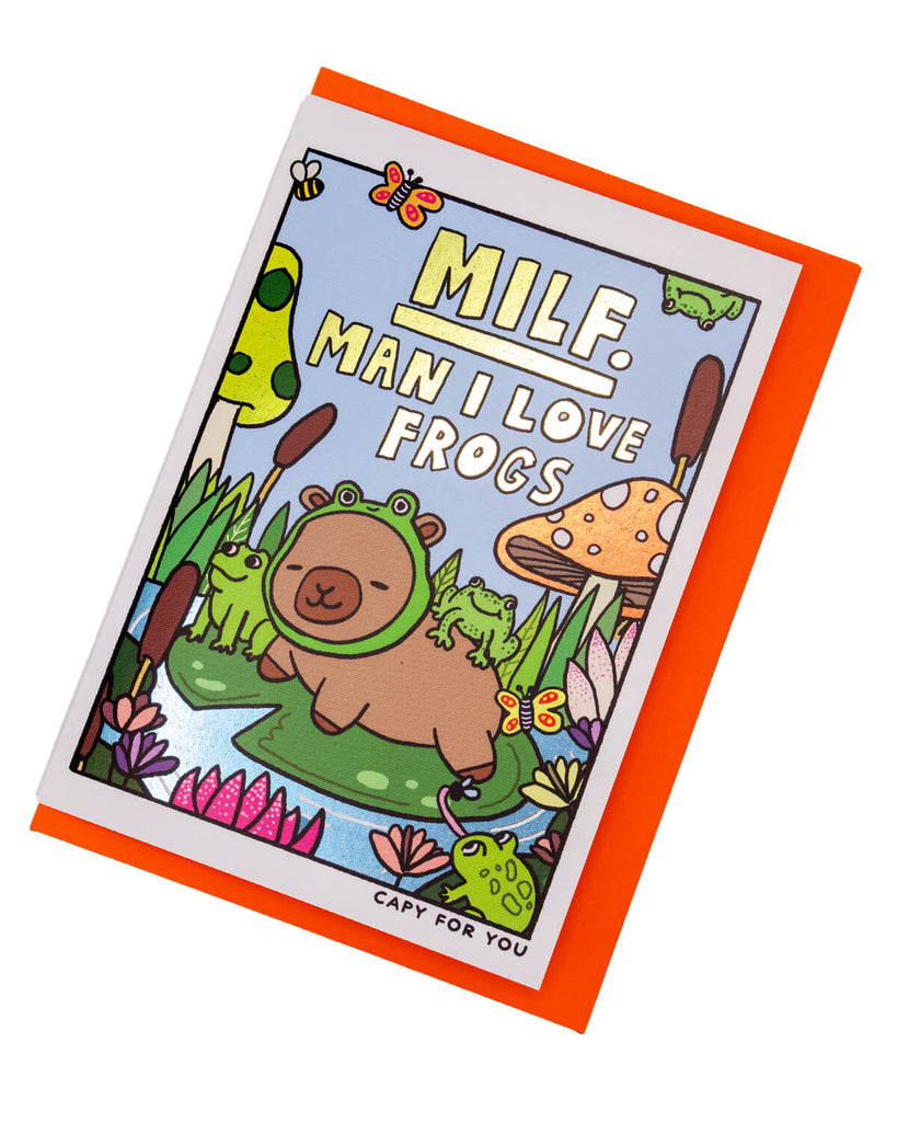 Funny A6 greeting card from Rebel Romance featuring a capybara dressed as a frog surrounded by actual frogs, mushrooms, and lily pads in a colourful pond scene. Includes bold foil text reading “MILF. Man I Love Frogs.” Perfect for quirky animal lovers, frog fans, and millennials with a cheeky sense of humour. Includes a bright orange envelope for extra pop.