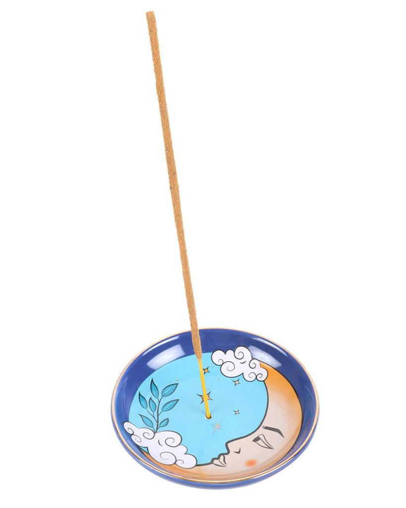 Close-up of the ceramic incense holder with a burning incense stick, highlighting the dreamy face of the moon and surrounding stars.