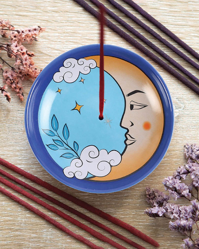 The Moon Celestial Incense Holder styled with incense sticks and dried flowers on a wooden surface, showcasing the vibrant blue moon design.